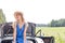 Woman looking away while sitting on convertible trunk against clear sky