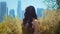 Woman looking back on skyscrapers standing in park. Asian lady enjoy city view.