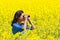 Woman looking through binoculars in blooming rapeseed field