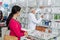 Woman Looking At Chemist Searching For Medicine In Shelves