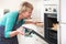 Woman Looking At Chicken Roasting In Oven