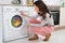 Woman Looking At Clothes Rotating Inside The Washing Machine