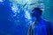 Woman looking at fish vortex in large public aquarium tank at oceanarium