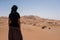 Woman looking at the horizon dunes in the Moroccan Sahara desert