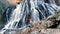 Woman looking on huge waterfall. Traveler rising her hands near waterfall