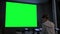 Woman looking at large blank green screen - chroma key concept