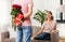 Woman looking at man with flowers and gift at home