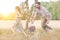 Woman looking at man playing with daughter on field at farmland and yellow lens flare in background