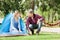 Woman Looking At Man Preparing Tent In Park