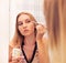 Woman looking in the mirror and putting make up on