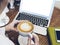 Woman looking on open laptop on wood table with empty blank screen monitor at home, person drink cup of coffee on background