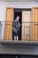 A woman looking out of her doorway atop a balcony in Puigcerda, Girona, Cataluna, Spain, Europe