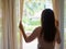 Woman looking out a window, indoors.