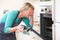 Woman Looking In Oven And Covering Eyes Over Disastrous Meal