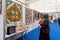 Woman is looking at a patchwork quilt hanging on a wall in the exhibition hall at a popular traditional city fair of handicraft.