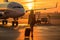 woman looking at plane , standing near the airport window, holding luggage. AI Generated