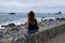 Woman looking at the rough sea on rocky beach