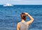 Woman looking at sea. Trendy casual photo of girl watching cruise boat.