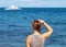 Woman looking at sea. Trendy casual photo of girl watching cruise boat.