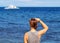 Woman looking at sea. Trendy casual photo of girl watching cruise boat.