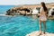 Woman looking on the stunning views from the famous Cape Greco viewpoint as she stands on the edge of a cliff