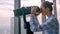 Woman looking through tourist telescope and exploring cityscape