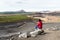 Woman looking at a volcanic landscape while sitting on a rock on the of a volcano