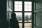 Woman looking through window, toned image, vintage style. Turin cityscape, Torino, Italy, old house, rear view in shade.