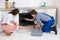 Woman Looking At Worker Repairing Oven