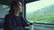Woman looks at the mountain landscape through the train window. Solo traveler, vacation concept
