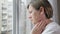 Woman looks out of window and touches painful spot on neck