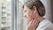 Woman looks out of window and touches painful spot on neck