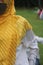 a woman looks trendy by wearing a yellow hijab with a yellow gold striped motif with a white shirt