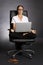 Woman in lotus pose in chair with laptop.