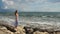 Woman in love standing on stones, stormy sea waves splashing, romantic mood