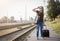 Woman with luggadge waiting on railway station for train on sunny day