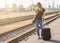 Woman with luggadge waiting on railway station for train on sunny day