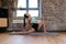 Woman in lunge pose doing yoga on mat indoors at home, trainer showing stretch exercise on low lunge