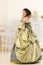 Woman in luxury vintage dress standing in bright room
