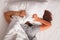 Woman lying in bed and covering her head with pillow.