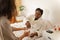 Woman lying in bed taking pills and water from caring nurse