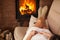 Woman lying in cozy warmth on a couch in front of fireplace