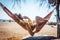 Woman lying in hammock close to the beach