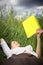 Woman lying in rapeseed field reading