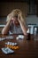 Woman lying at the table, depressed, lonely, sick, despondent, unhappy, suffering, among pills