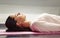 Woman lying on yoga mat relaxing her muscles