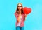 Woman makes an air kiss with a red balloon in the shape of a heart