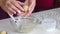 A woman makes candy from marzipan. Rolls balls of almond flour and powdered sugar with his hands. Places in tartlets. Close-up