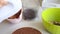 A woman makes cream for a chocolate cake with peanuts and strawberries. The ingredients for cooking are laid out on the table