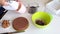 A woman makes cream for a chocolate cake with peanuts and strawberries. The ingredients for cooking are laid out on the table